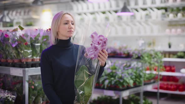 A Woman Chooses an Orchid for Home Gardening