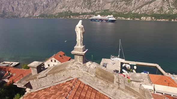 Statue of the Virgin Mary on the Roof of the Church in Prcanj Against the Backdrop of the Bay