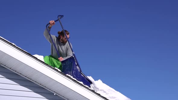 Removing Fresh Snow From a Roof in a Sunny Winter Day