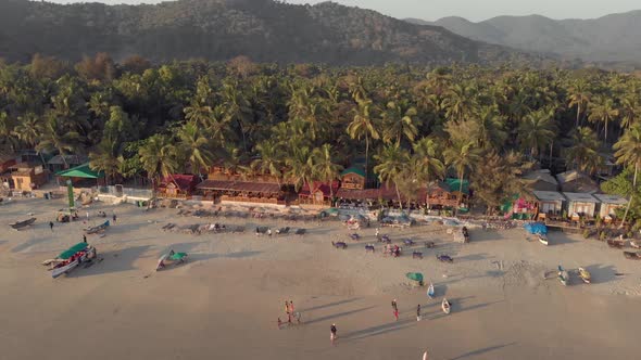 Drone footage panning a beach at sunset in Palolem, India busy with visitors from all over the world