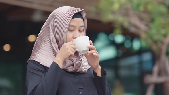 Muslim Asian working women drinking coffee in the morning with a happy face.