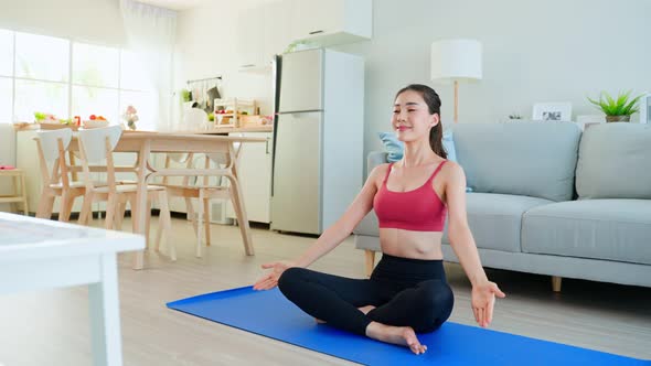 Asian young beautiful active woman exercise, doing Yoga Pilates follow workout instruction video.