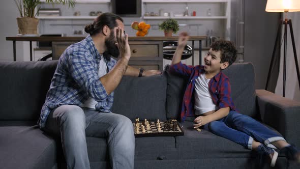 Excited Son Defeated Joyful Father in Chess Game