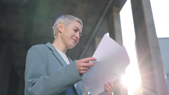 Woman Standing Near Office Center with Documents in Hands