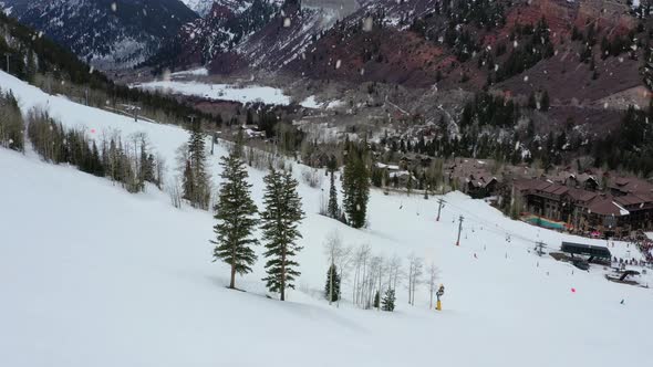 Beautiful skiing resort town in massive mountain valley during snowfall, aerial view