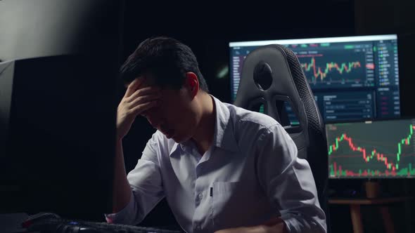 Disappointed Of Asian Male Stock Market Broker Working On Computer With Analyzing Graphs