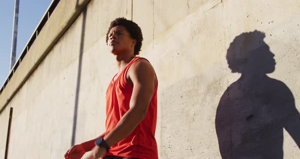 Fit african american man exercising outdoors in city, bouncing basketball
