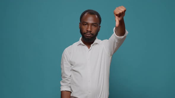 Negative Person Doing Thumbs Down Gesture in Studio