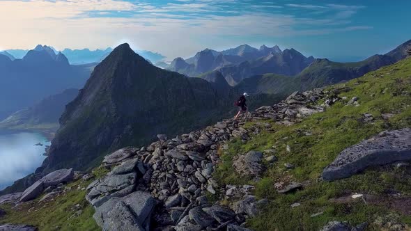 Aerial View of Girl with a Backpack Rises on a Mountain Ridge