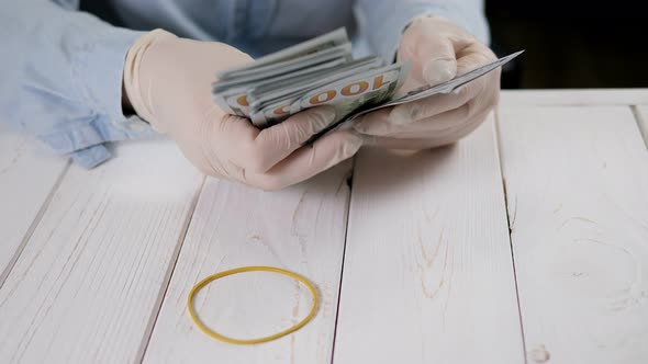 Closeup of a Woman in Gloves Counting Hundreddollar Bills