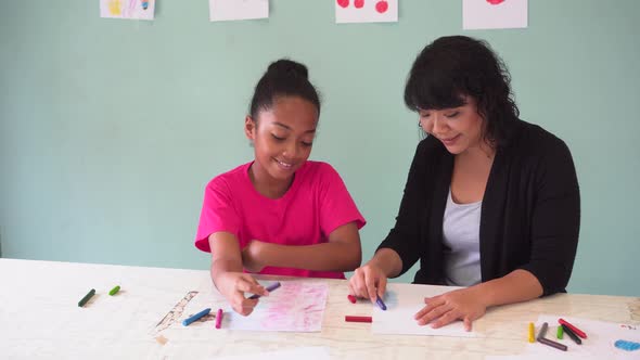 Young Teacher Giving African American Kid an Art Lesson and Teaching How to Draw