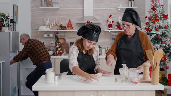 Grandparents Helping Granddaugher Preparing Traditional Homemade Dough