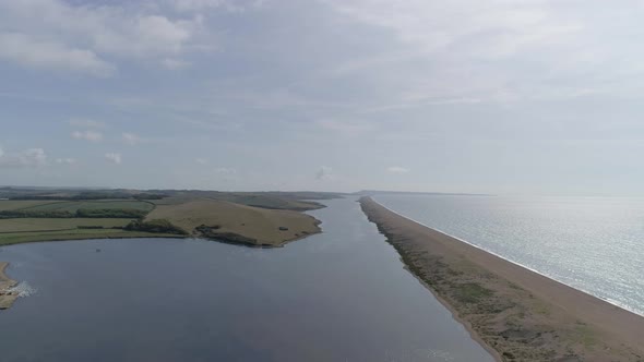 Aerial tracking forward over the vast fleet lagoon at Abbotsbury. to the right you can see the lengt