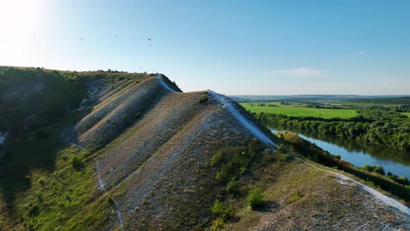 Flight Over Green Hills Fields and White Road on a Sunny Day