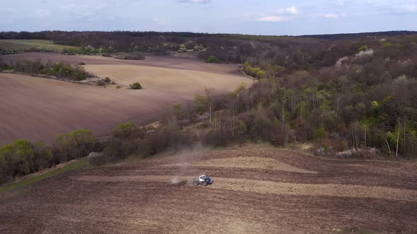 Aerial view large tractor cultivating a dry field. Top down aerial view tractor cultivating ground