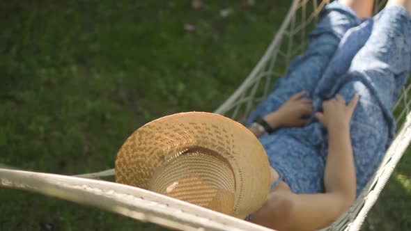 woman wearing a straw hat swings in a hammock. Slowmotion