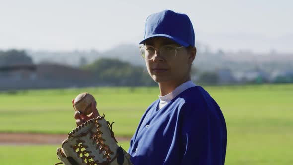 Portrait of caucasian of female baseball player, pitcher, holding ball in glove on field