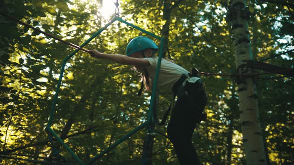 A Little Girl Walking on the Rope Bridge and Holding By the Ropes