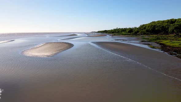 Forward aerial of shallow water and sandbanks by Rio de la Plata shore