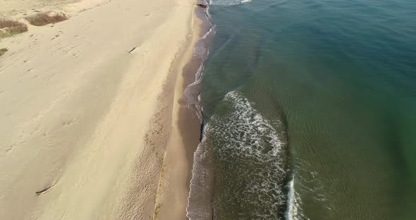 Aerial view of tropical beach, foamy ocean waves washing sand. Waves hitting sand beach