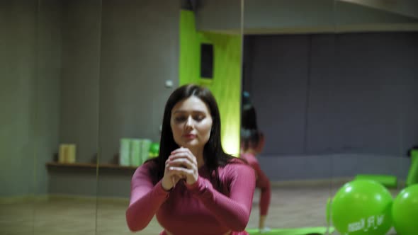 Young Woman in Pink Costume Squatting in the Mirror Fitness Hall