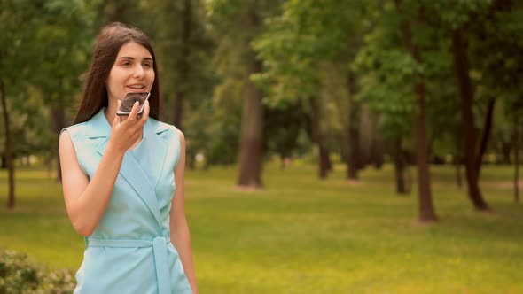 Businesswoman Dictates Voice Message Walks Along Alley with Trees