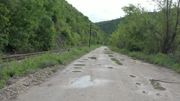 Dirt road nearby railway track and telephone line poles 4K aerial video