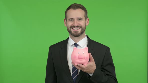 Young Businessman Holding Piggy Bank Against Chroma Key