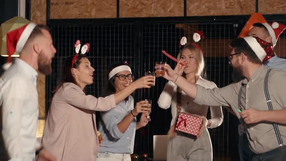 Company of Young Friends Are Celebrating Christmas Clicking Glass with Alcohol