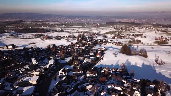 Panorama flight over a village with a church not far from the lake of Zurich.