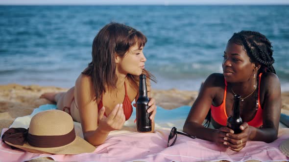 Student Girls Lying on Beach Drinking Beer