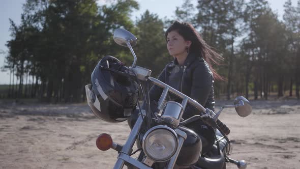 Pretty Caucasian Girl Sitting on the Motorcycle Looking Away