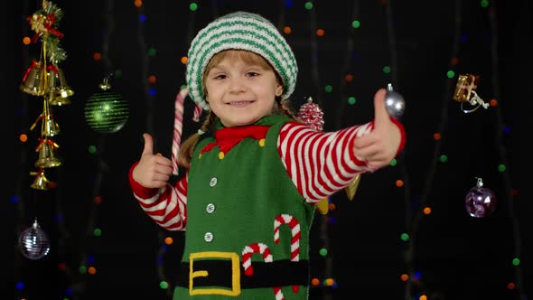 Teen Kid Girl in Christmas Elf Santa Claus Helper Costume Showing Thumbs Up on Black Background