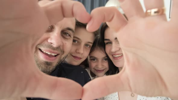 Dad and Mom Make a Heart with Their Hands and Look at the Camera