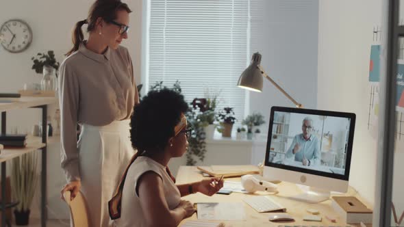 Two Multiethnic Businesswomen Video Calling on Computer in Office