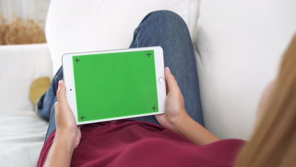 Young asian woman using black tablet device with green screen. Asian woman holding tablet