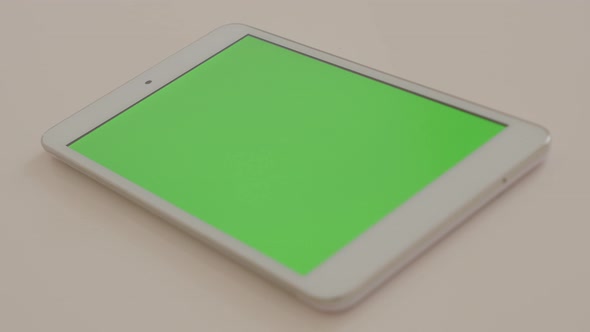 Modern PC tablet with greenscreen  display on white reflective surface slow panning 4K 3840X2160 Ult