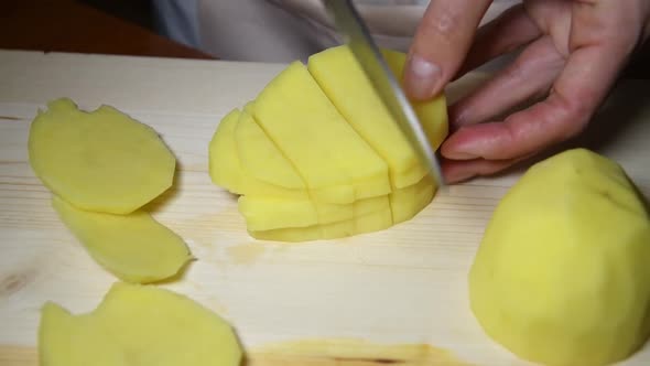 autentic female hands cutting a potato by knife on cutting board