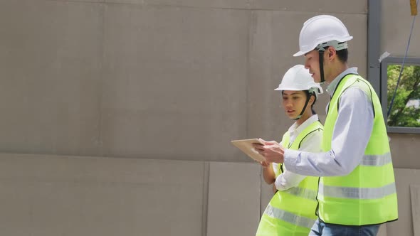 Asian colleague workers people wearing protective safety helmet and glasses onsite of architecture.