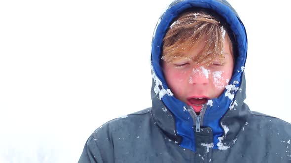 a Young Teenager Man of Caucasian Ethnicity in Warm Winter Clothes Stands in a Snowy Park and