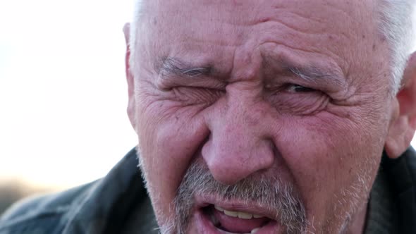 Close-up portrait of a gray-haired elderly man with wrinkles.