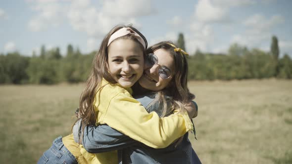 Camera Approaches To Two Happy Joyful Young Hippie Women Hugging Outdoors Smiling Camera