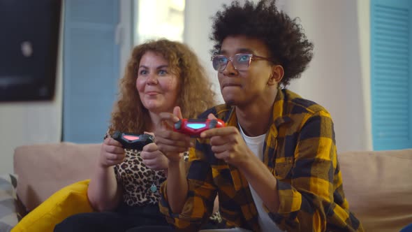 Cheerful Diverse Couple Competing with Each Other in Video Games, Holding Joysticks and Laughing