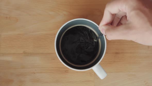 Stirring a cup of coffee on wooden cutboard