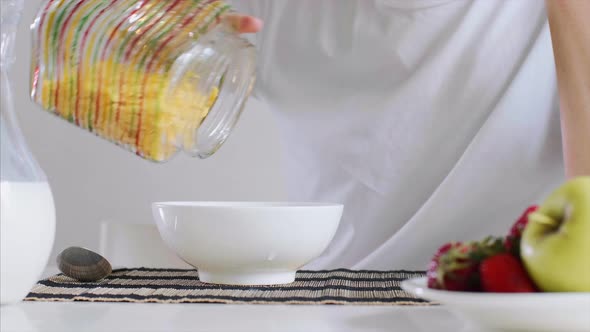 Woman's Hand Is Pouring Milk and Cornflakes in a Bowl for Breakfast.