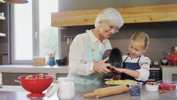 Happy grandmother and granddaughter preparing pie 4k