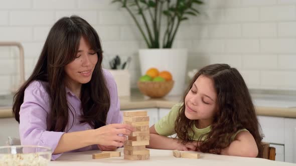 Joyful Mother and Happy Daughter are Playing a Board Game at Home at the Table Removing Wooden