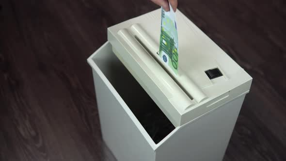 Shredder Destroys One Hundred Euro Bill. A Man Thrusts Money Into a Paper Shredder