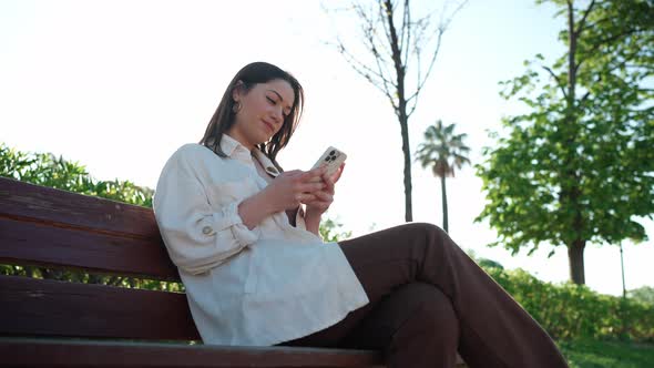 Positive brunette woman typing on mobile