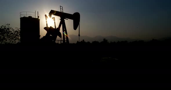 Industrial oil pump jack pumping crude oil for fossil fuel energy with drilling rig in oil field.